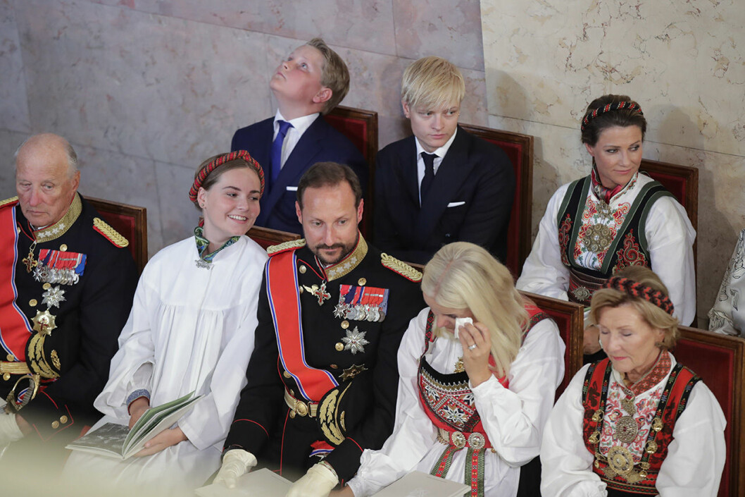 En rörd Mette-Marid torkar bort en tår under konfirmationen. Drottning Sonja, kronprinsessan Mette-Marit, kronprins Haakon, prinsessan Ingrid Alexandra, kung Harald, prinsessan Astrid, prinsessan Märtha Louise, Marius Borg och prins Sverre Magnus