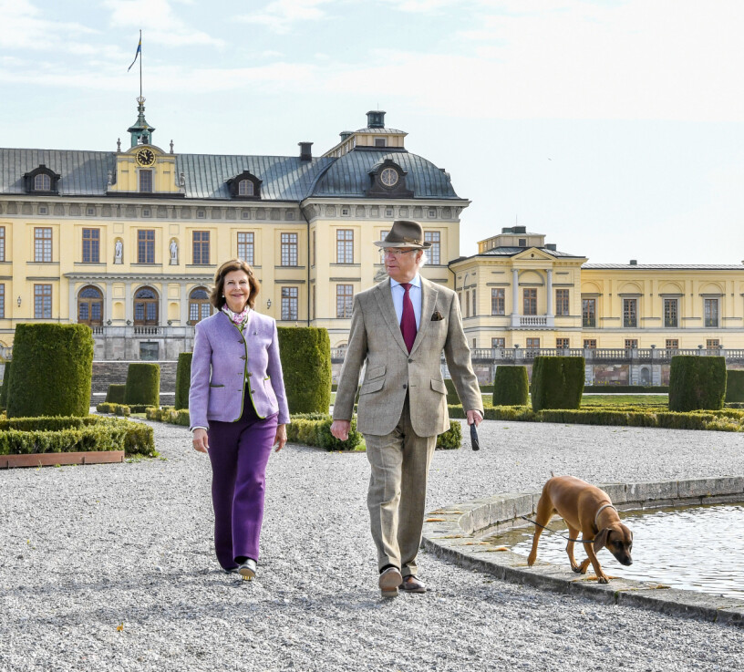 Kungaparet framför slottet. Nedre Sjöflygeln ligger längre ner till höger, precis utanför bild. Kungen, drottningen och hunden Brandie framför Drottningholms slott