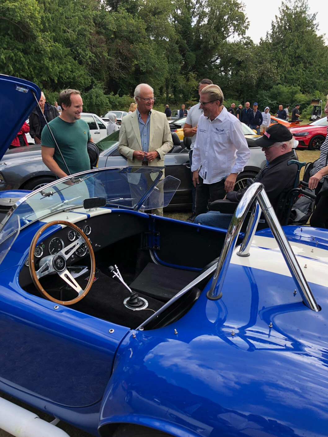 Kungen står och pratar med Mikael Lorenssen (till höger i bild) och tittar på hans AC cobra 427 sc, årsmodell 1966. Söndagen den 4 augusti närvarade kungen och drottningen vid entusiastfordonutställningen i Sollidens slottspark.