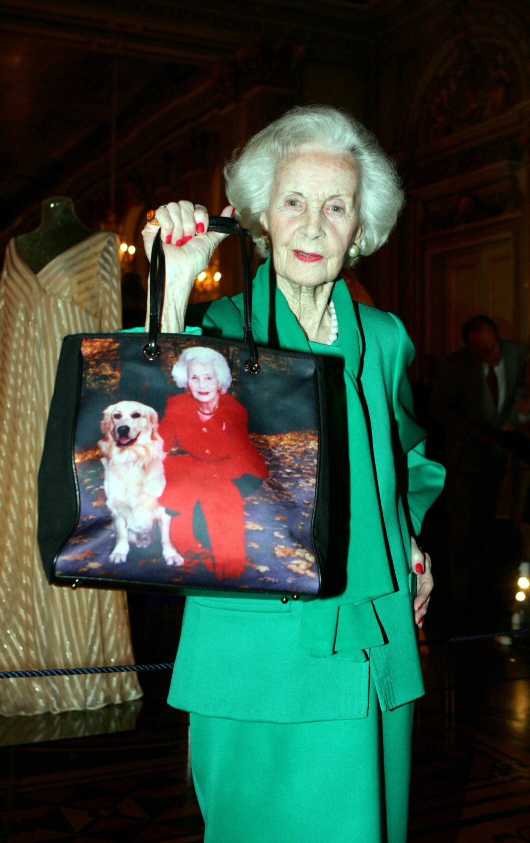 Prinsessan Lilian lät tillverka denna underbara väska med ett porträtt på henne själv och hunden Bingo. Hon var också modeintresserad och hade en magnifik, färgstark garderob som senare kom att visas upp för allmänheten på Kungliga slottet i utställningen Kläder för en prinsessa – The Lilian Look! Prinsessan Lilian med en väska med motiv av henne själv och en hund