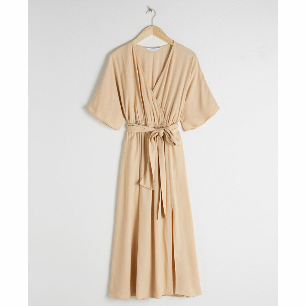 Beige halvlång klänning med knytdetalj i midjan från & Other Stories.<a href="https://track.adtraction.com/t/t?a=1279077969&as=1267646502&t=2&tk=1&url=https://www.stories.com/en_sek/clothing/dresses/wrap-dresses/product.belted-kimono-wrap-midi-dress-beige.0773179001.html" target="_blank" rel="noopener"> Här kan du läsa mer och köpa den</a>. Ljus beige halvlång klänning med knytrosett i midjan