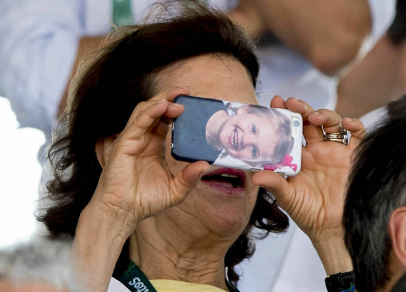 Drottning Silvia tar en bild med sin mobil som har prinsessan Estelle på mobilskalet