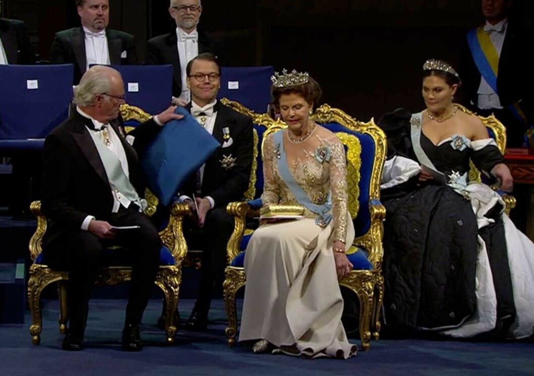 Kudden byter plats. Och bakom sitter prins Daniel och försöker hålla masken… Kungen satt på fel plats i Konserthuset under Nobel 2019.