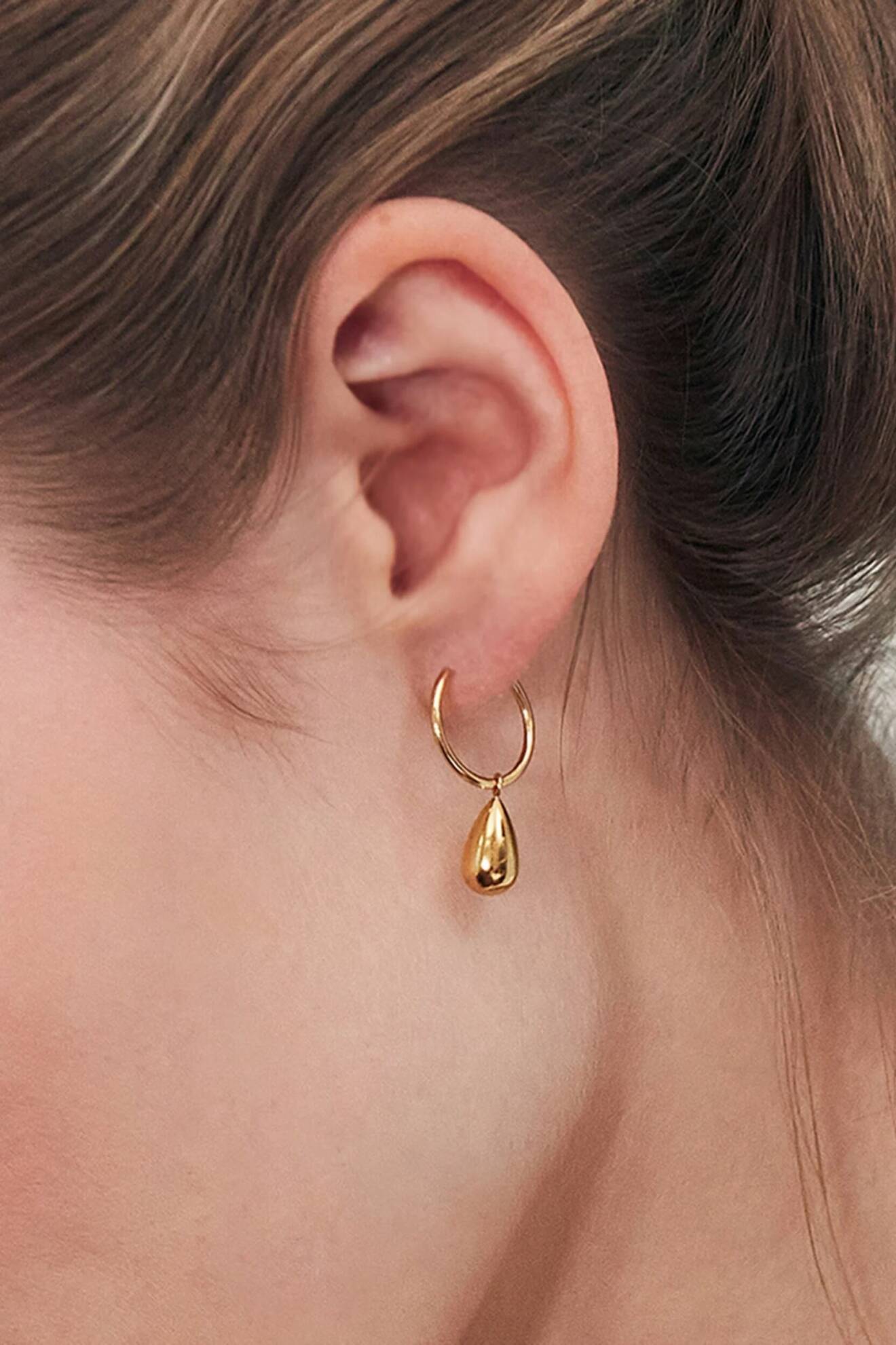 guldfärgade örhängen med dropformad design från edblad