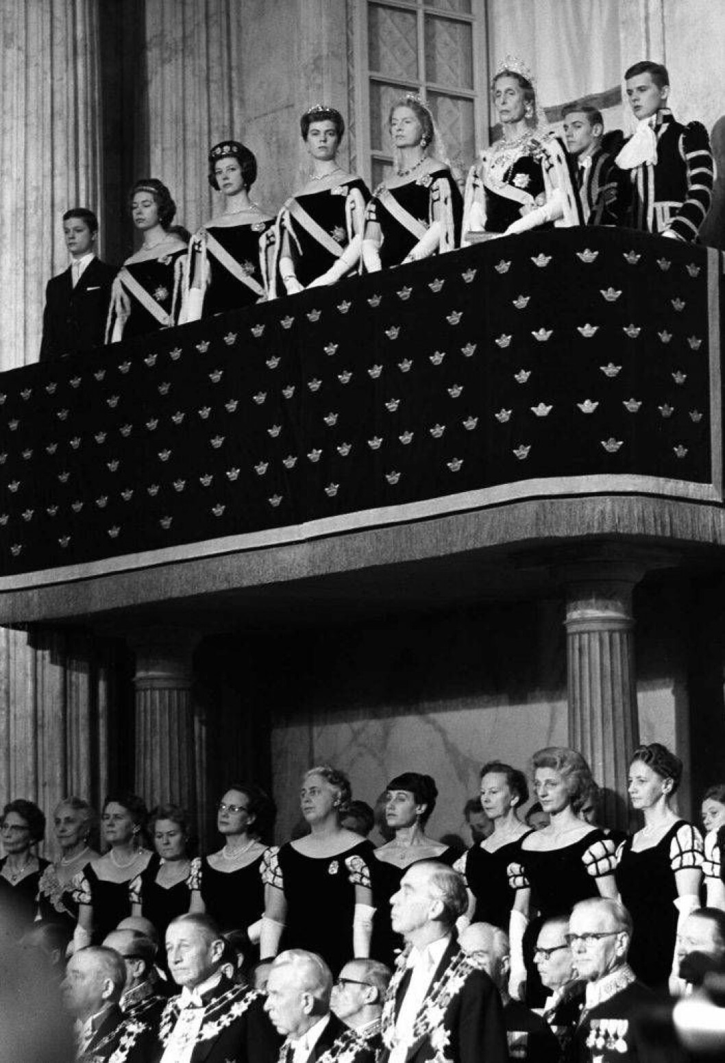 Rikssalen på Stockholms slott och riksdagens högtidliga öppnande 1962. På drottningläktaren från vänster: Kronprins Carl Gustaf, prinsessorna Christina, Desirée, Margaretha, Sibylla, drottning Louise och kammarpagerna. Statsrådinnorna har sin plats under balkongen. Längst till vänster står statsministerns hustru Aina Erlander. Rikssalen