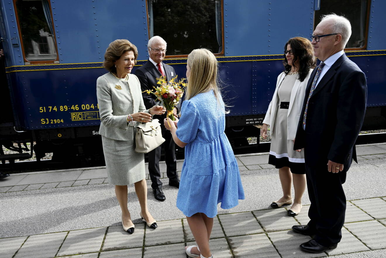 Drottning Silvia och kung Carl Gustaf tar emot blommor när de klivit av tåget i Gävle