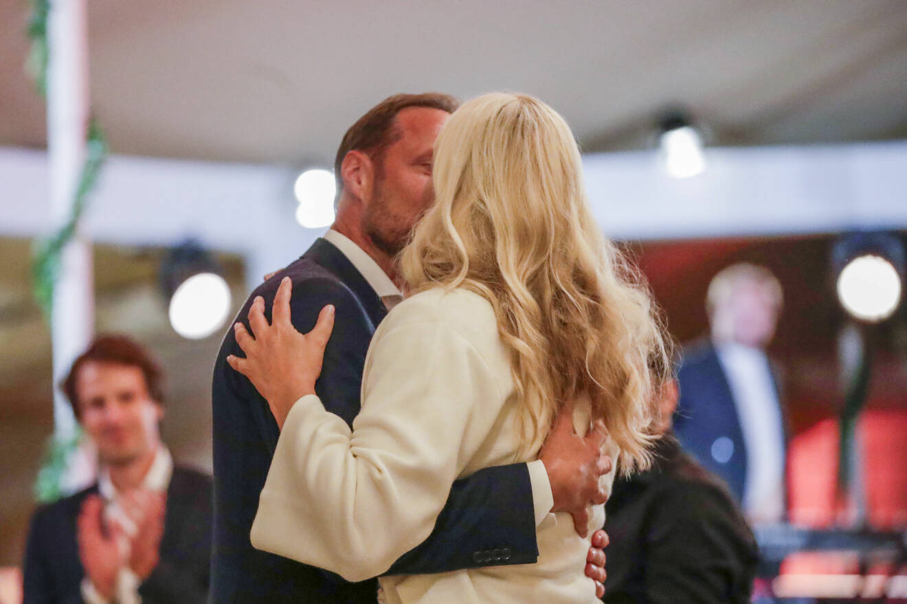 Kronprinsessan Mette-Marit och kronprins Haakon kysser varandra under bakgårdsfesten på Slottet i Oslo på fredagen.
