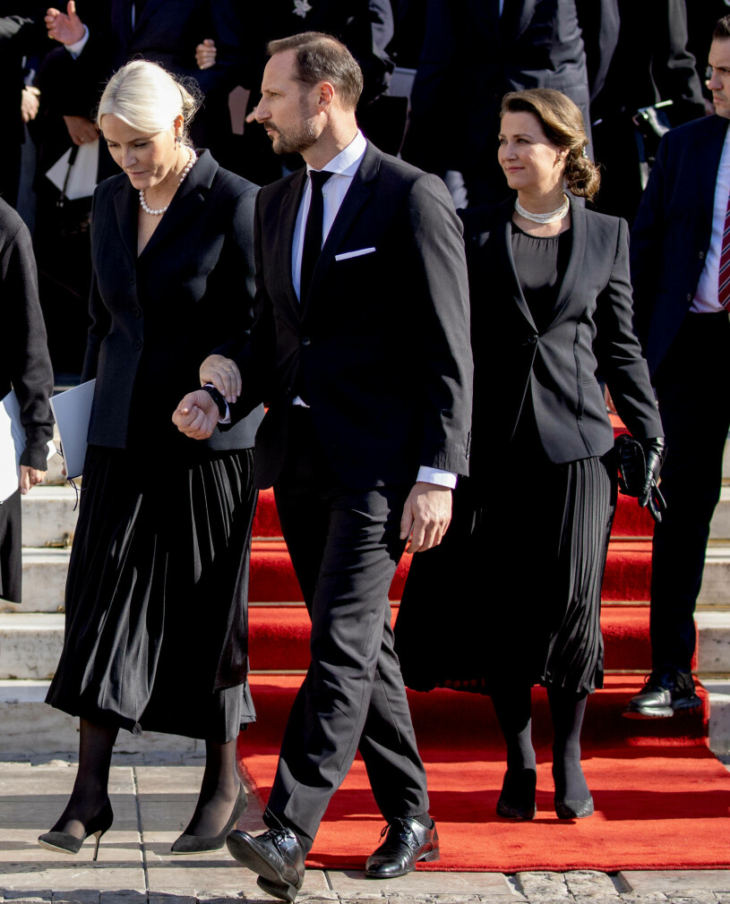 Kronprinsessan Mette-Marit och prinsessan Märtha Louise i klädkrock på kung Konstantins begravning i Aten