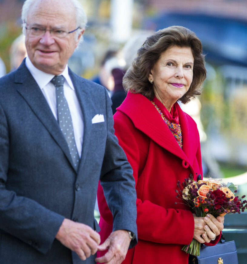 Kungen och drottning Silvia reser land och rike runt. Kungaparet med kungen i kostym och drottning Silvia i röd kappa