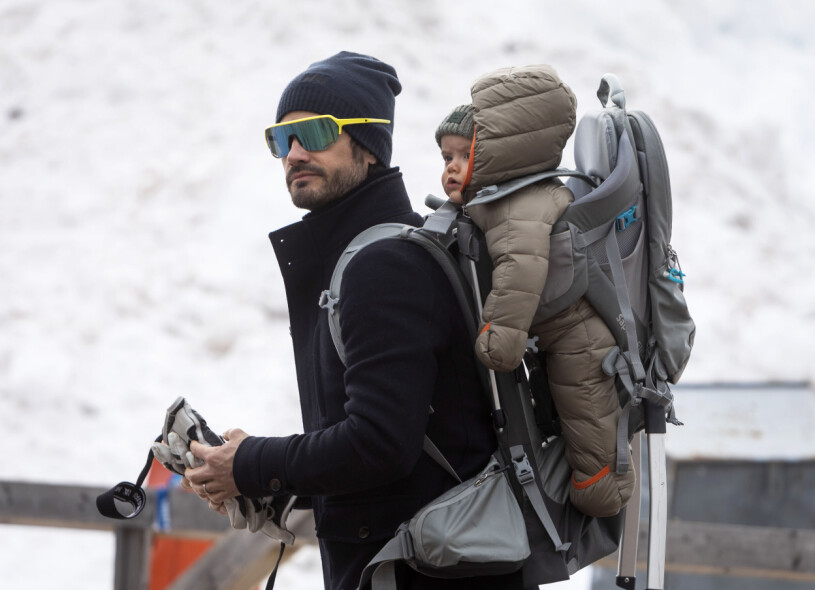 Carl Philip och lille Julian på samma plats i Evertsberg för ett år sedan. Prins Carl Philip bar prins Julian på ryggen när han besökte Vasaloppets kontroll i Evertsberg under söndagen.