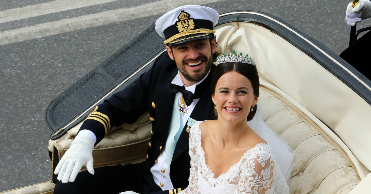 Prins Carl Philip och prinsessan Sofia ler mot kameran i bröllopskortegen