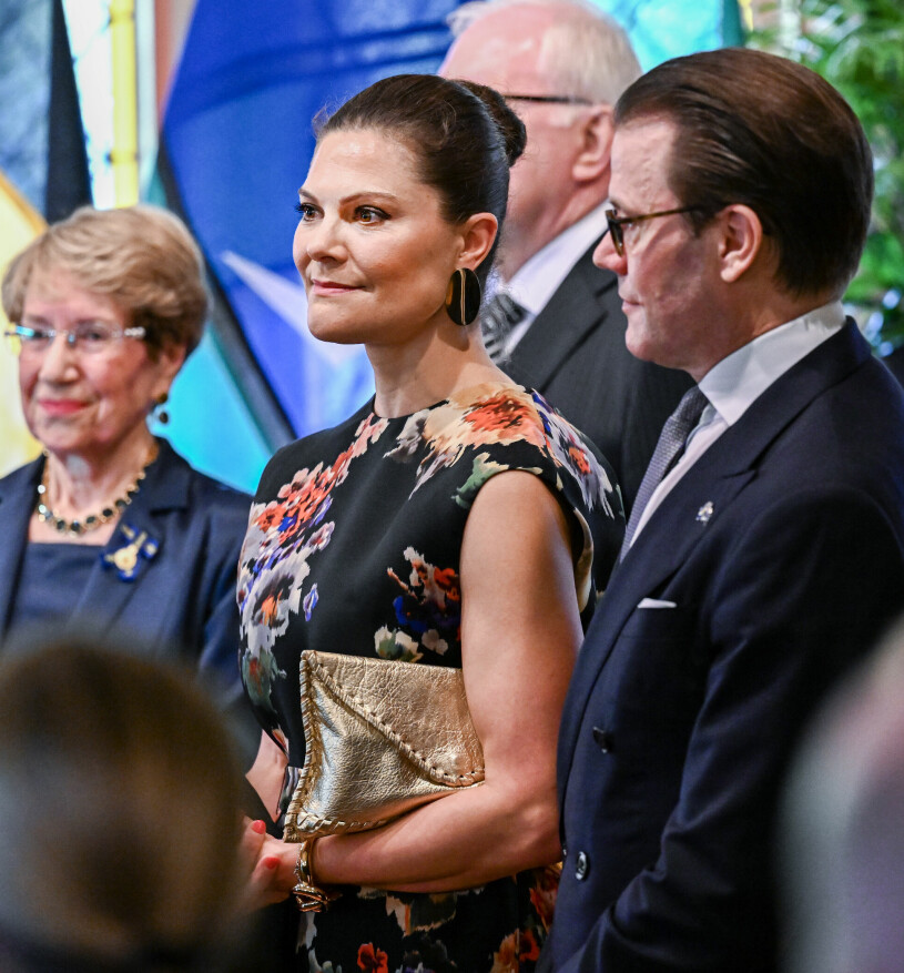 En allvarlig Victoria med guld-clutchen i ett fast grepp. Kronprinsessan Victoria och prins Daniel på fest i Sydney, Australien