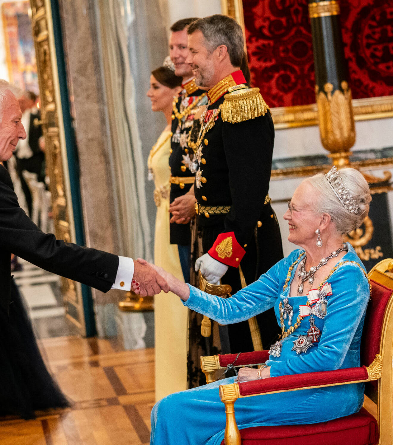 Drottning Margrethe hälsar sittande i en stol