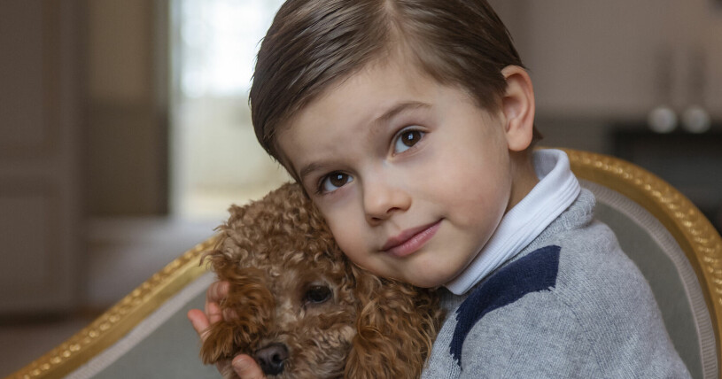 En lite mindre prins Oscar med en liten mindre hund Rio. Prins Oscar kramar kronprinsessfamiljens hund Rio