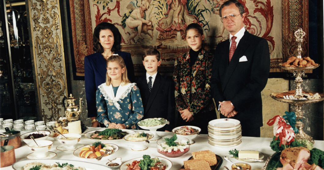 Kungafamiljen står stolt och visar upp sitt julbord som innehåller klassiska inslag som lax, julskinka och sill. Kung Carl Gustaf, prins Carl Philip, drottning Silvia, prinsessan Madeleine och kronprinsessan Victoria
