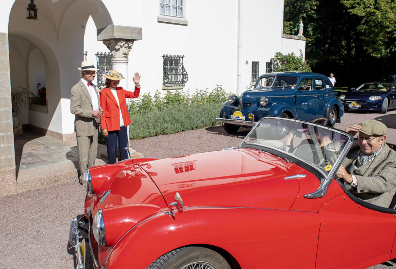 Kungsrallyt rullar in på Solliden. I bakgrunden ser du kungens blåa Volvo från 1946. Kungen Drottningen Svenska Kungsrallyt 2021