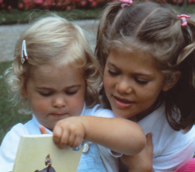 Blonda Madeleine, 2, i skrindan med sin betydligt mörkare storasyster Victoria, 7, en sommardag på Solliden år 1984. Prinsessan Madeleine Kronprinsessan Victoria Solliden 1984 Hårfärg