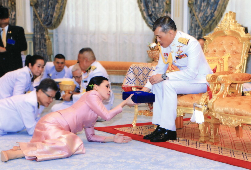 Kungen på sin tron. Och på golvet fru nummer fyra, drottning Suthida. Thailands kungafamilj Kung Vajiralongkorn. På golvet drottning Suthida en av hans fruar
