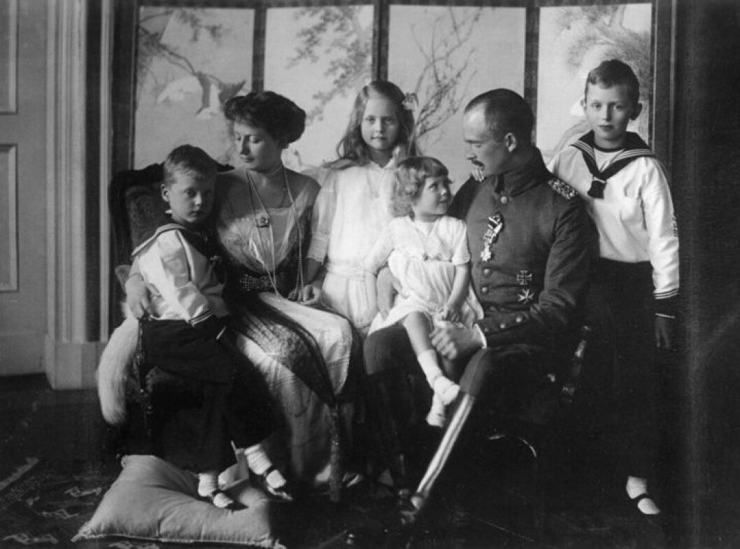 En bild på hela familjen. Prinsessan Sibylla står i bakgrunden och prinsessan Caroline Mathilde sitter i sin fars knä. Calma