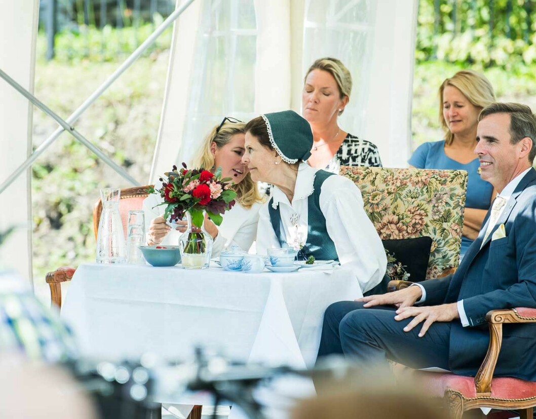 Kaffebordet var dukat. Bakom drottningen ser du hennes hovdam Harriet Bredelius (i blått) och till höger sitter Ekerös kommunalråd Adam Reuterskiöld. Drottningen på de Gamlas dag, här med hovdamen Harriet Bredelius (i blått) och Ekerös kommunalråd Adam Reuterskiöld.