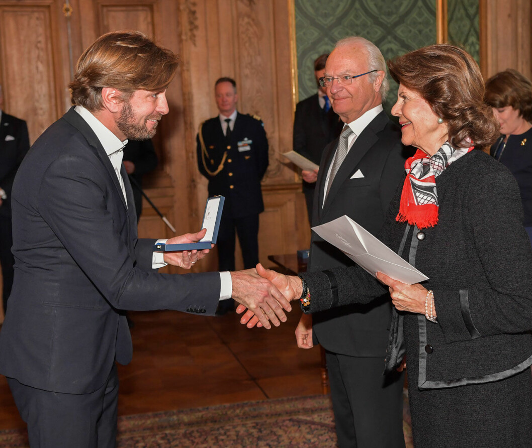 Medaljceremonin för medarbetarna vid hovet var mindre och mer personlig än den här, som ägde rum dagen före i Lovisa Ulrikas matsal. Då fick (bland andra) regissören Ruben Östlund, Sveriges Radios vd Cilla Benkö och Spotifygrundaren Martin Lorentzon ta emot sina medaljer. Regissören Ruben Östlund får medalj av kungen.