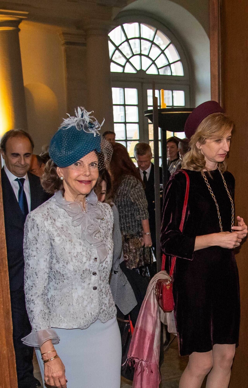 Drottning Silvia i grå dräkt och chic hatt med flor.