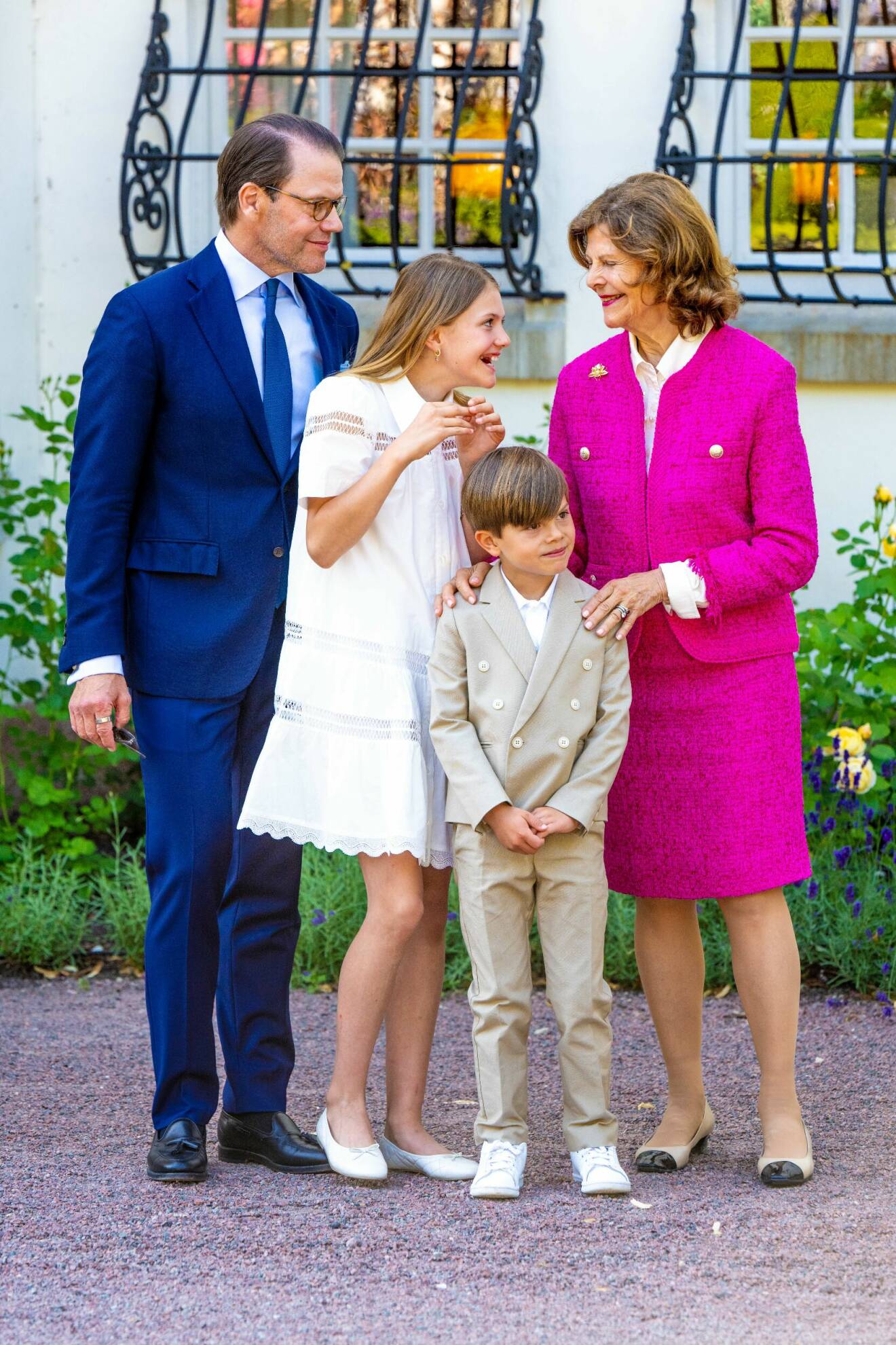 Prins Daniel tittar på när drottning Silvia och prinsessan Estelle skojar med varandra. Drottning Silvia håller händerna på prins Oscars axlar