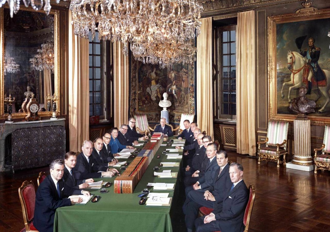 Samma rum 1966, med Gustav VI Adolf som konseljens ordförande. Titta noga så ser du att precis allting är sig likt. Skifteskonseljerna har ju ägt rum här i konseljsalen på Stockholms slott sedan år 1870. Skifteskonseljerna har ägt rum i konseljsalen på Stockholms slott sedan 1870. Och innan dess var detta Gustaf III:s matsal. Här leder Gustav VI Adolf skifteskonseljen år 1966.