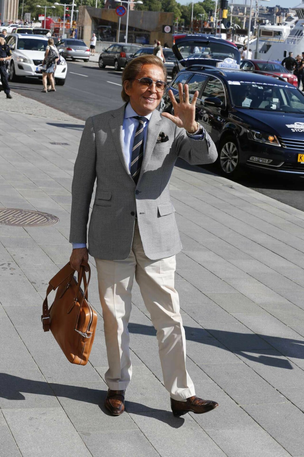 Här vinkar modeskaparen världsvant utanför fashionabla lyxhotellet Grand Hotel i Stockholm. Här vinkar modeskaparen världsvant utanför fashionabla lyxhotellet Grand Hotel i Stockholm.