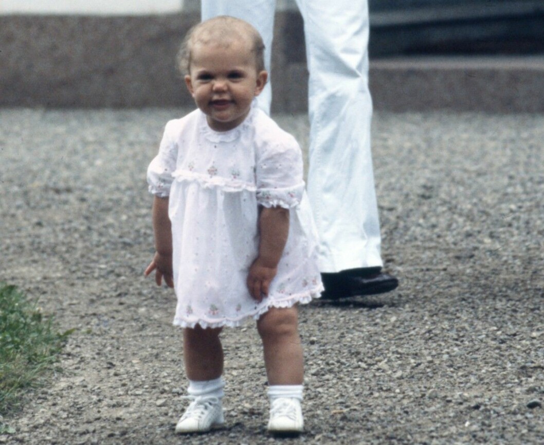 Kronprinsessan Victoria på ettårsdagen. Kronprinsessan Victoria, 1 år. Hon är fotad framför slottet Solliden och har en rosa klänning på sig.