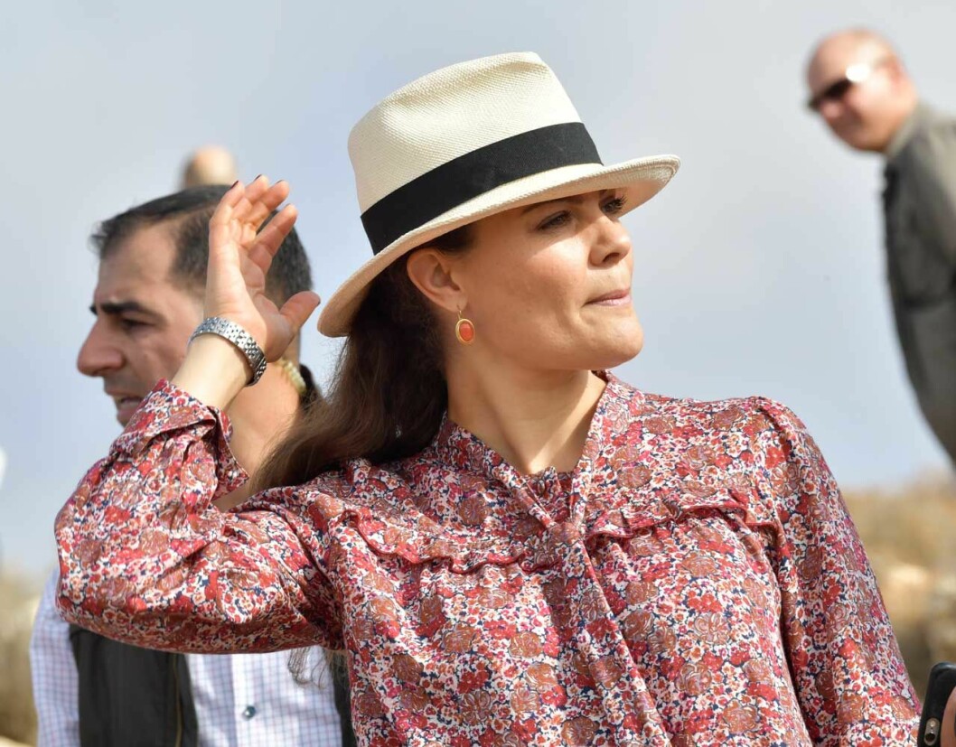 Den här coola hatten blev räddningen när solen gassade som värst. Det finns ett väloljat maskineri runt Victoria och Daniel och adjutanten ser till att bra-att-ha-sakerna är inom räckhåll. Adjutanten ser till att kronprinsessan Victoria får sin hatt när hon behöver den.