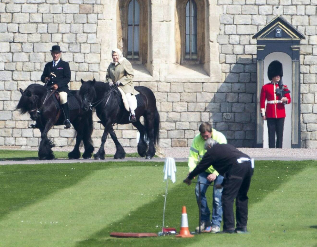 Drottning Elizabeth rider förbi några byggjobbare på Windsor Castle.
