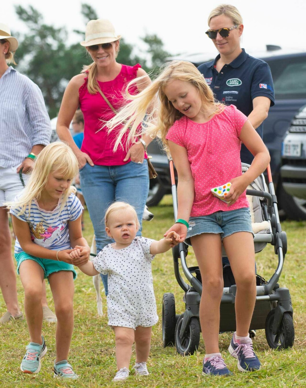 På bilden ser vi Isa och Savannah som hjälper lilla Lena att gå, bakom dem ser vi deras mödrar Zara Tindall och Autumn Phillips som ser till att allt går bra. zara tidal autumn Phillips barn